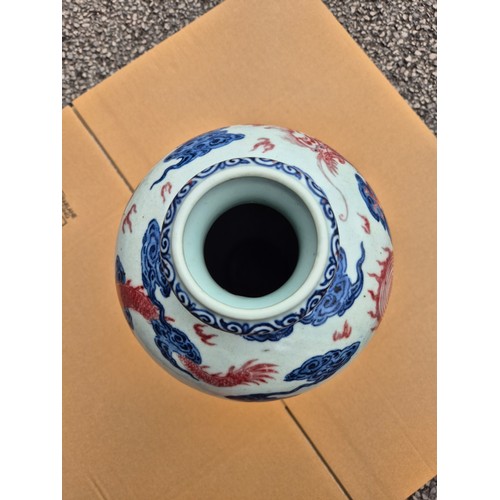 614 - A Chinese porcelain baluster vase decorated in red and blue underglaze depicting a dragon amongst cl... 