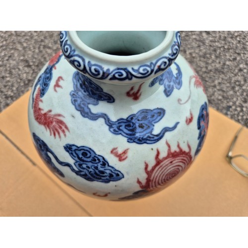 614 - A Chinese porcelain baluster vase decorated in red and blue underglaze depicting a dragon amongst cl... 