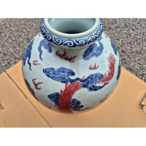 614 - A Chinese porcelain baluster vase decorated in red and blue underglaze depicting a dragon amongst cl... 