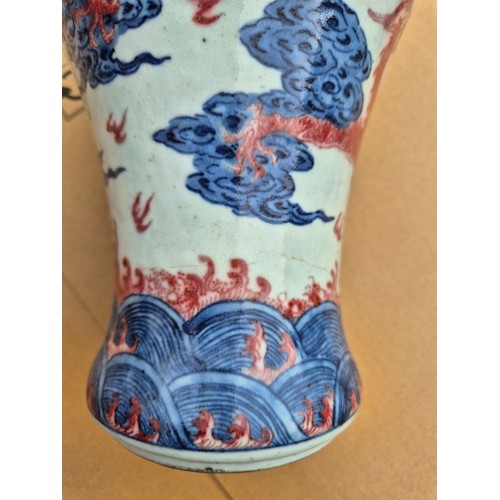 614 - A Chinese porcelain baluster vase decorated in red and blue underglaze depicting a dragon amongst cl... 
