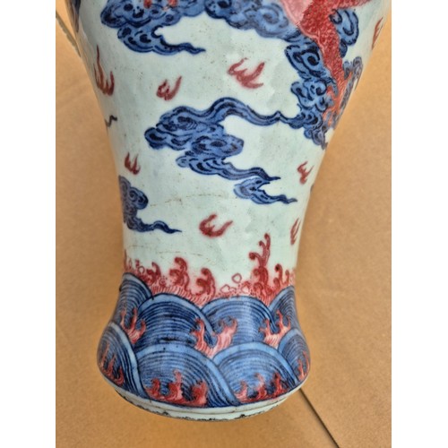 614 - A Chinese porcelain baluster vase decorated in red and blue underglaze depicting a dragon amongst cl... 