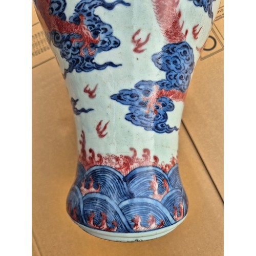 614 - A Chinese porcelain baluster vase decorated in red and blue underglaze depicting a dragon amongst cl... 