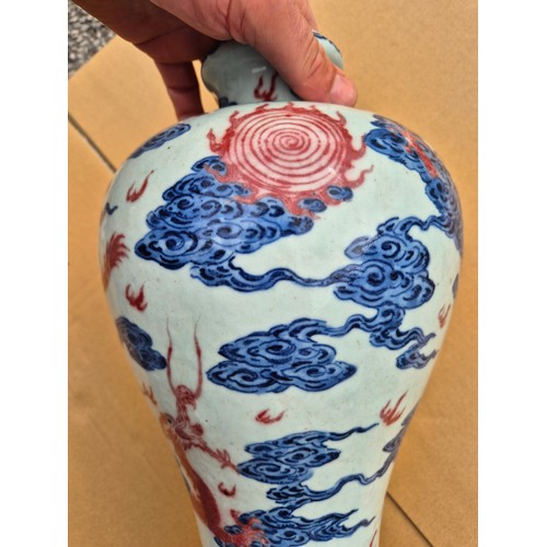 614 - A Chinese porcelain baluster vase decorated in red and blue underglaze depicting a dragon amongst cl... 