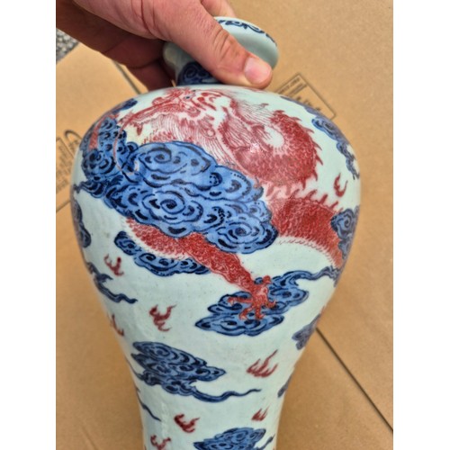 614 - A Chinese porcelain baluster vase decorated in red and blue underglaze depicting a dragon amongst cl... 