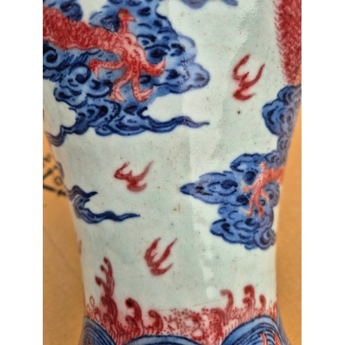 614 - A Chinese porcelain baluster vase decorated in red and blue underglaze depicting a dragon amongst cl... 
