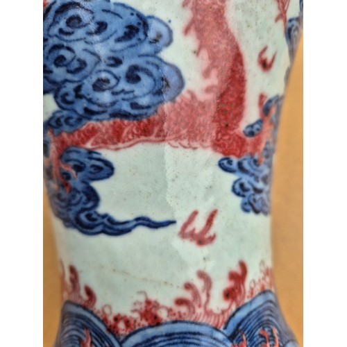 614 - A Chinese porcelain baluster vase decorated in red and blue underglaze depicting a dragon amongst cl... 