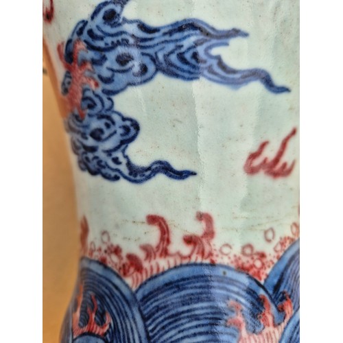 614 - A Chinese porcelain baluster vase decorated in red and blue underglaze depicting a dragon amongst cl... 