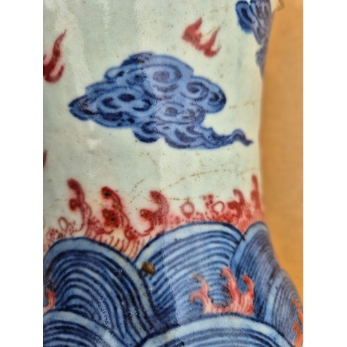 614 - A Chinese porcelain baluster vase decorated in red and blue underglaze depicting a dragon amongst cl... 
