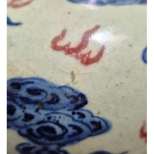 614 - A Chinese porcelain baluster vase decorated in red and blue underglaze depicting a dragon amongst cl... 