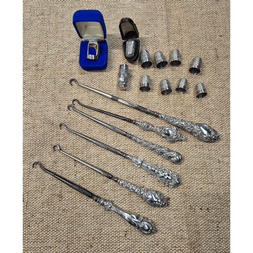 454 - Six hallmarked silver handled button hooks, eight silver thimbles and a white metal needle case.