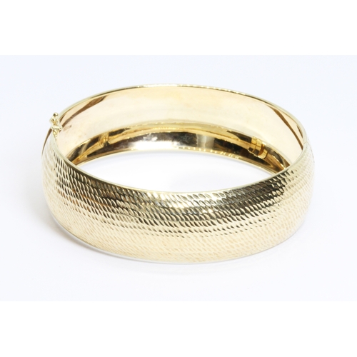 25 - An engraved bangle, marked '9K', diameter 6cm, weight 12.4g.