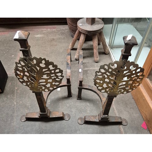 44 - A pair of cast fire dogs with ornate pierced brass ornamental fronts