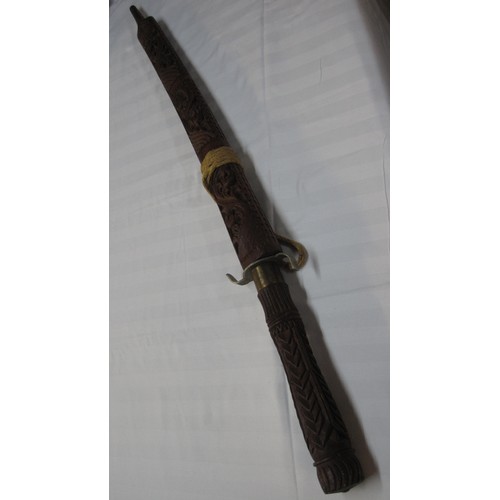 141 - An interesting Asiatic sword in an ornately carved wooden scabbard