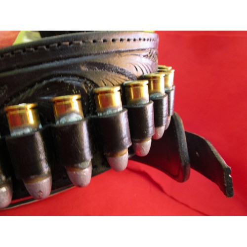 224 - An ornately tooled heavy leather Western gunbelt and holster with bullet hoops, the hoops populated ... 