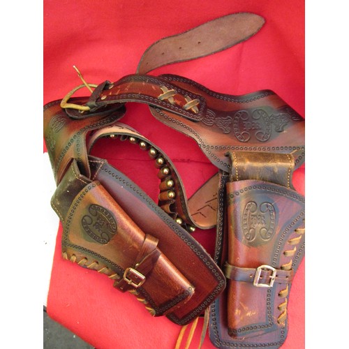 225 - A heavy leather ornately tooled Western gunbelt in brown leather with holsters for 2 guns, the bulle... 