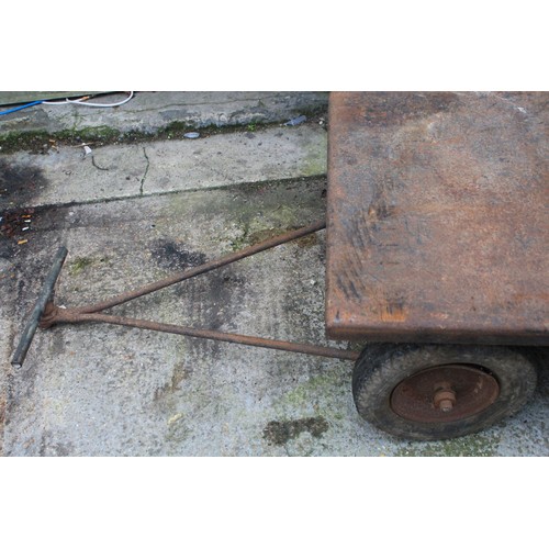 185 - A large and heavy cast iron trailer with 4 pneumatic tyres, possibly an ex-RAF WW2 bomb trailer