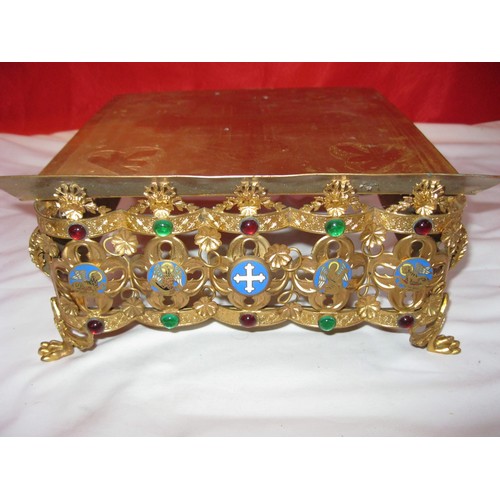 19 - A polished brass bible holder, the top inscribed with a crucifix and with enamelled religious motifs... 