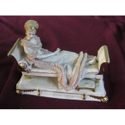 49 - German Porcelain figurine of a lady reclining on a day bed.
Some damage to frill work around the low... 