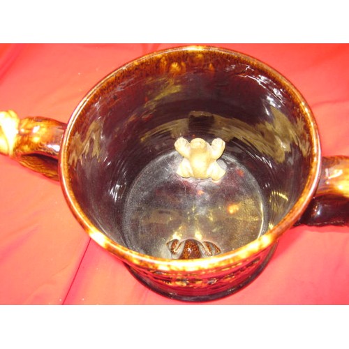 93 - A treacle ware two handled loving cup with internal frogs approx nine inches across by 6 high