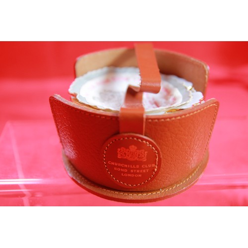 213 - A small leather holder marked Churchill's Club, Bond Street, London containing 4 ashtrays/pin dishes... 