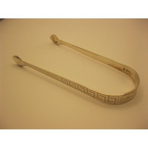 228 - A substantial pair of sugar tongs in sterling silver, embellished with Greek Key design to handle, h... 