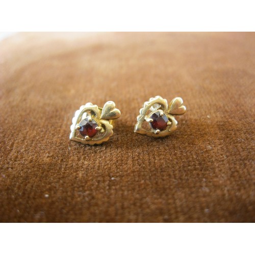 242 - A pair of heart shaped earrings in 9 carat gold set with a central ruby, approx weight 1.2g