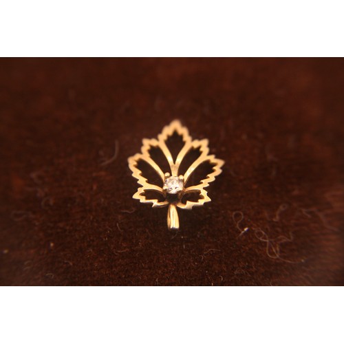117 - A 9 carat gold pendant in the form of a maple leaf, with clear stone to centre