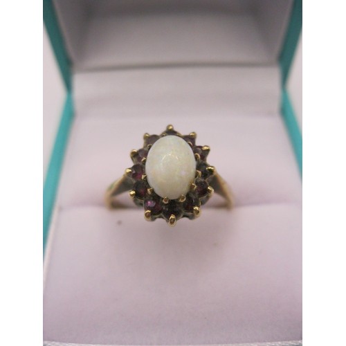 127 - A 9 carat gold ring set with an opal of good size surrounded by either rubies or garnets, size O/P, ... 