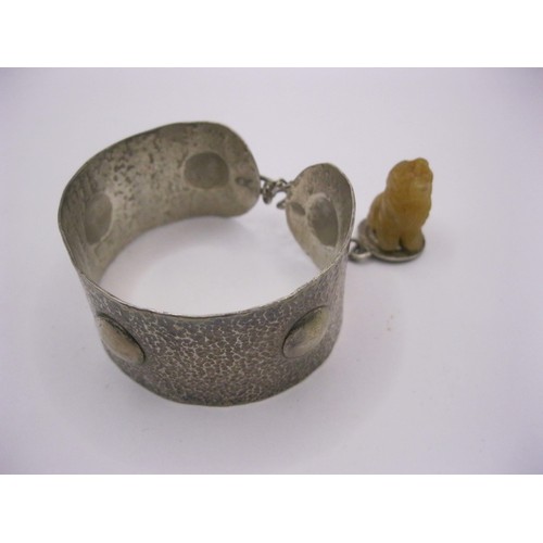99 - A bangle in .800 grade silver with an attached charm of a small dog in resin or similar