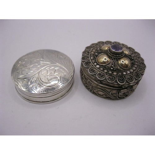 106 - A pair of sterling silver snuff- or pill-boxes, one very ornate with a lilac stone - possibly amethy... 