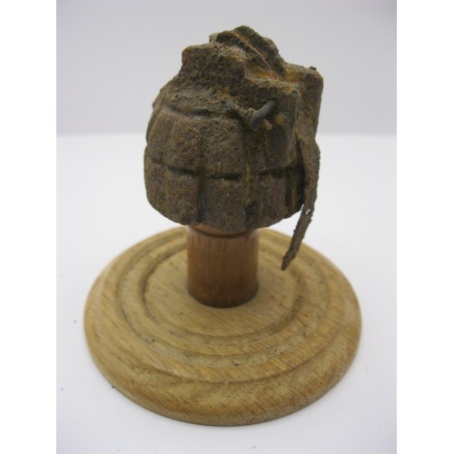 233 - A WW1 hand grenade in relic condition (casing only) mounted on a wooden stand