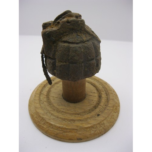 233 - A WW1 hand grenade in relic condition (casing only) mounted on a wooden stand