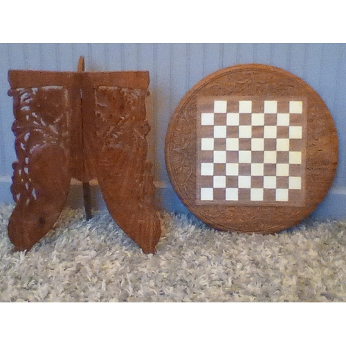 307 - A hand carved hard wood chess table with peacock design fretwork on 3 hinged folding legs, 18