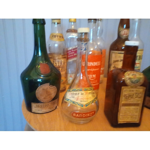 313 - A collection of vintage alcohol bottles with a good variety of original labels intact