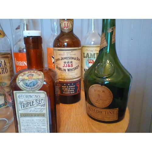 313 - A collection of vintage alcohol bottles with a good variety of original labels intact