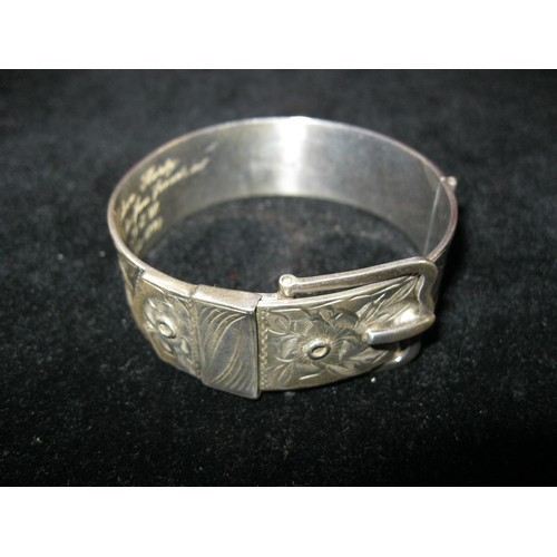 186 - A substantial silver bangle in the form of a belt and buckle with floral engraved decoration, inscri... 