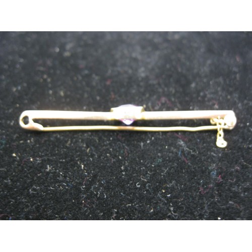 190 - A 15 carat gold bar brooch with central amethyst or similar stone in reeded mount, approx weight 3.2... 