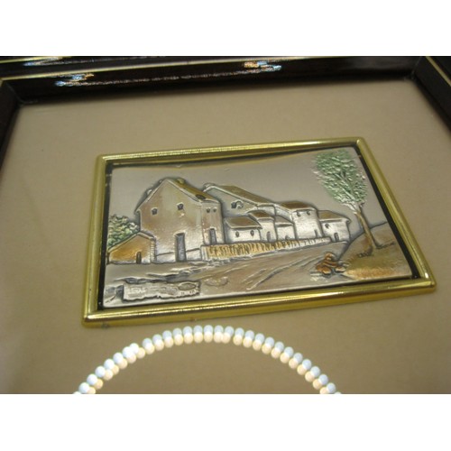 179 - A pair of embossed and tinted white metal pictures - road and houses and boats at quayside, each wit... 