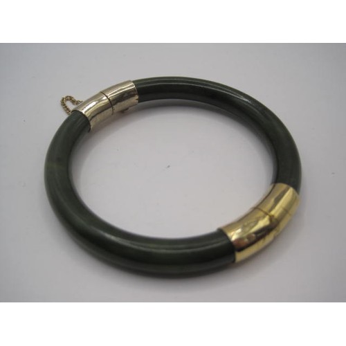 221 - A beautiful dark green jade and gold bangle with safety chain