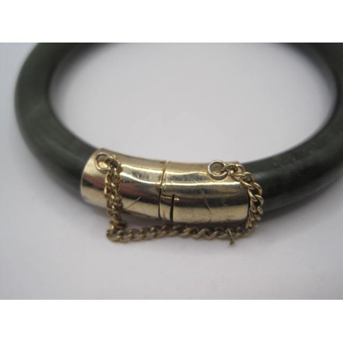 221 - A beautiful dark green jade and gold bangle with safety chain