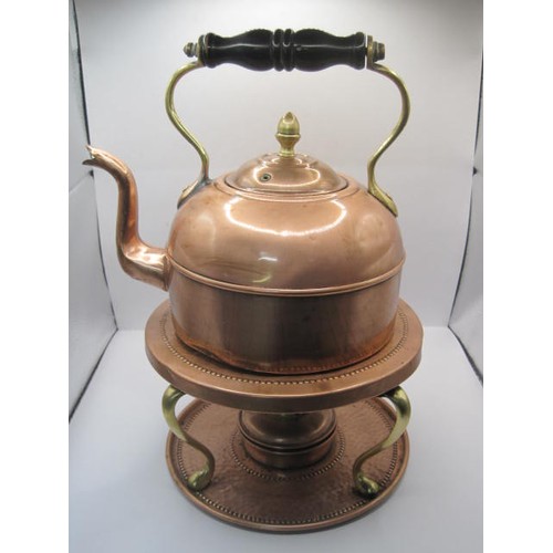 39 - A hand hammered copper kettle with rivetted handle with a matching spirit burner in decorated heatin... 