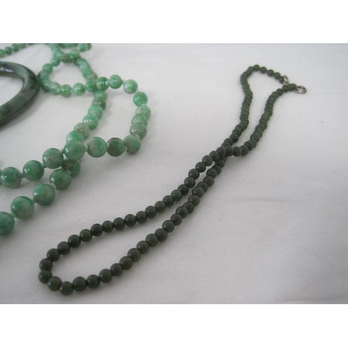 118 - A polished green jade bangle (external diameter 7.6cm)
a necklace of graduated glass beads, opaque g... 