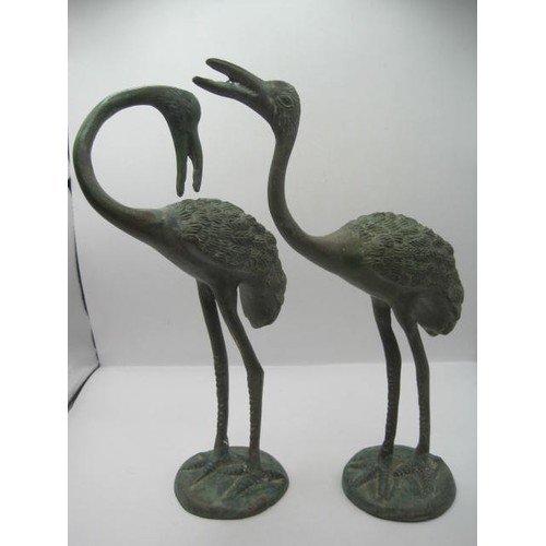 134 - A pair of verdigris bronze birds, perhaps storks or herons, on round bases, heights 26cm and 25cm