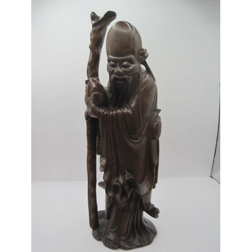 145 - Chinese or Far Eastern carved wood figure of robed wise man with staff and bag, height 28.5cm. Sligh... 