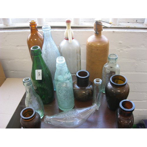 141 - A selection of Green, Brown and Clear vintage advertising bottles along with a ceramic version, incl... 