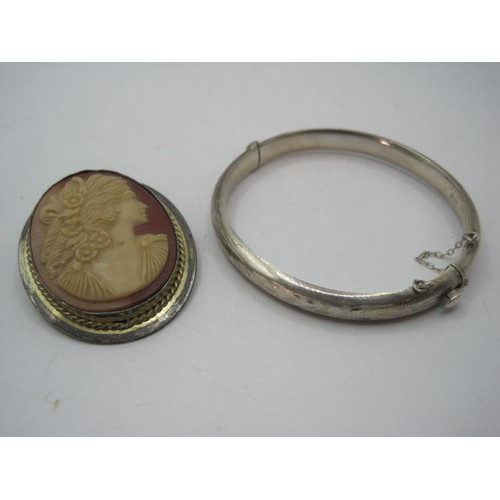 33 - A silver bangle and a silver-mounted cameo brooch - the half-engraved silver bangle with safety chai... 