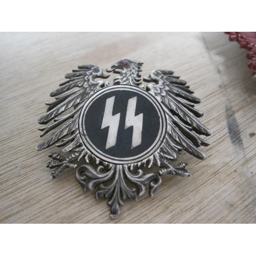 A painted badge featuring a swastika: a swastika with ring mount marked ...