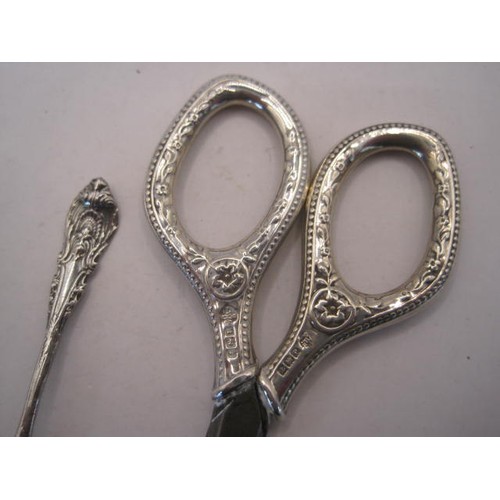 249 - Silver handled sewing scissors and a condiment spoon - the scissors with steel blades, embossed silv... 