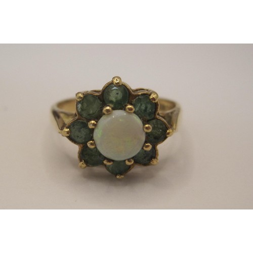 164 - A 9 carat gold ring with central opal surrounded by 8 emeralds, approx weight 3.1g