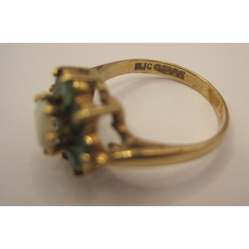 164 - A 9 carat gold ring with central opal surrounded by 8 emeralds, approx weight 3.1g